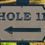 Close-up of a directional sign for Hole 11 on a golf course in daylight.