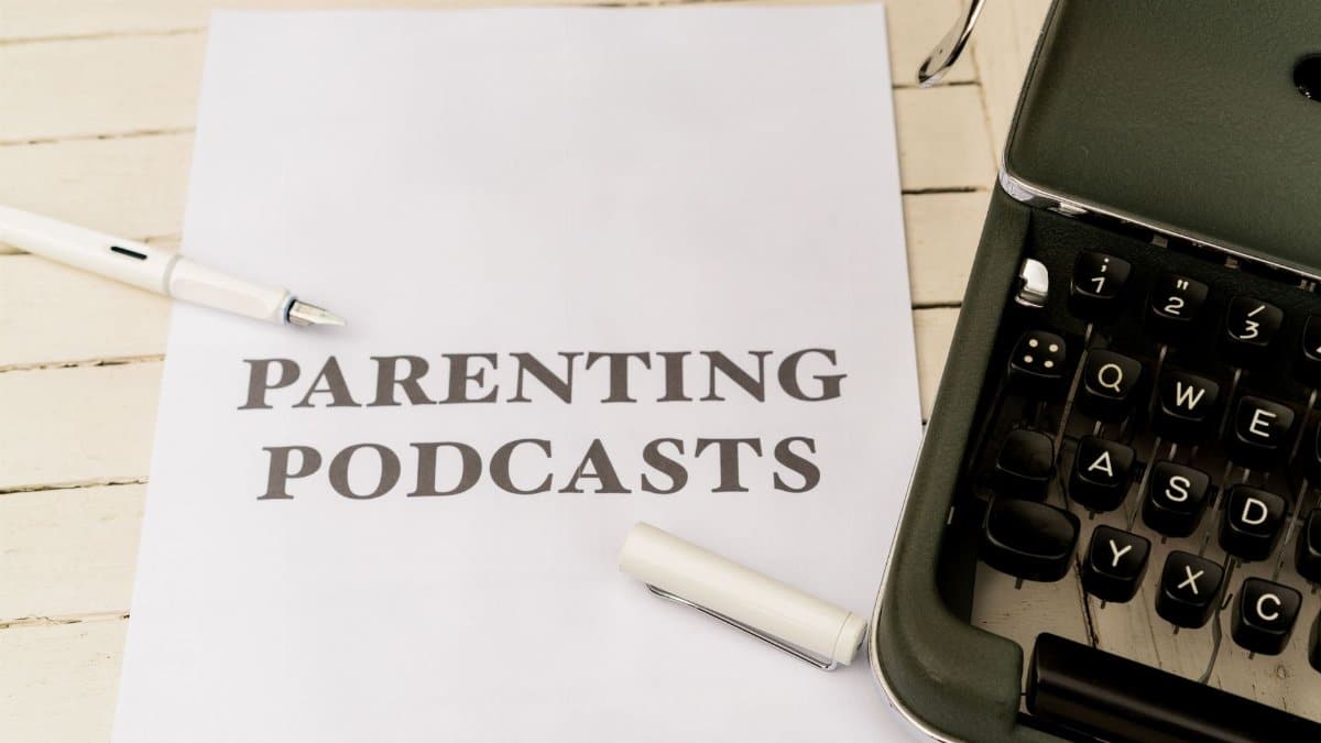 A vintage typewriter with a paper labeled 'Parenting Podcasts' on a wooden desk.