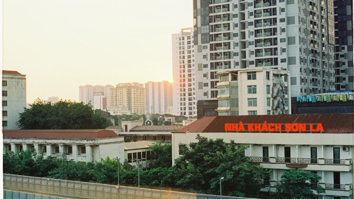 Capture of Hanoi city buildings with NHÀ KHÁCH SƠN LA sign at sunset.