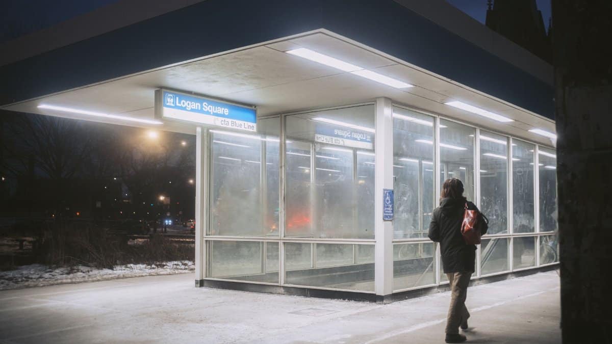 Person entering Logan Square CTA Blue Line station at night in winter.