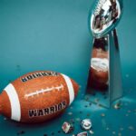 Football and trophy with championship rings on a celebratory background.
