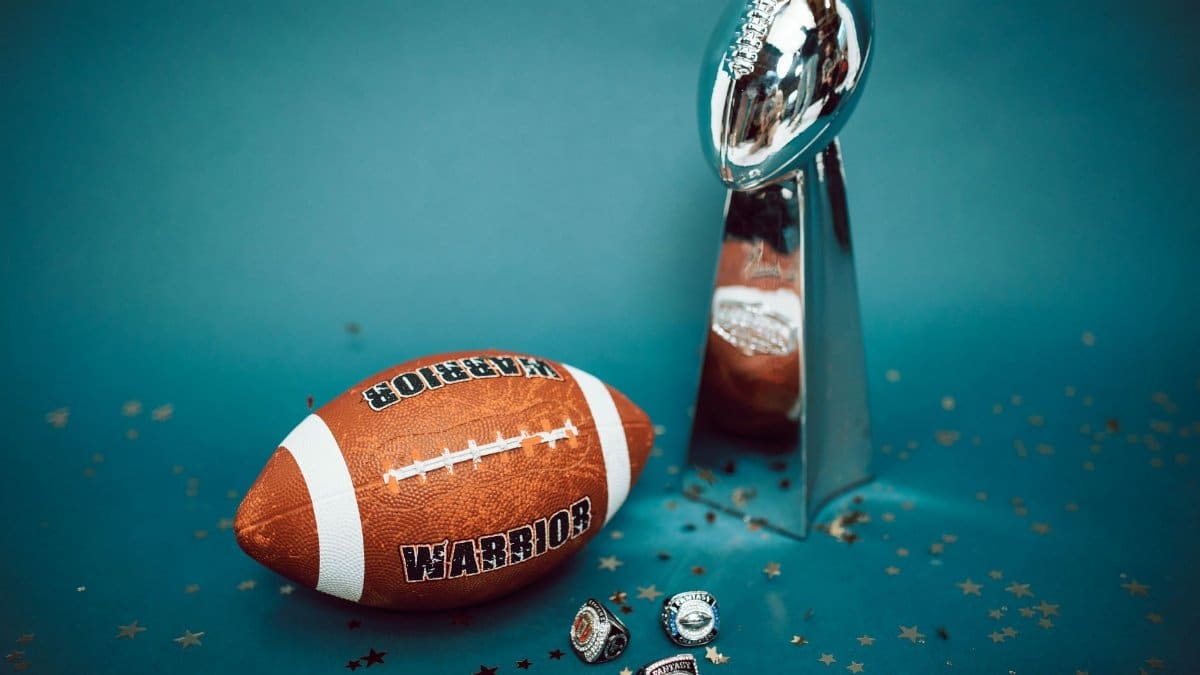 Football and trophy with championship rings on a celebratory background.