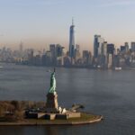 An aerial view of the iconic Statue of Liberty with New York City's skyline in the background.