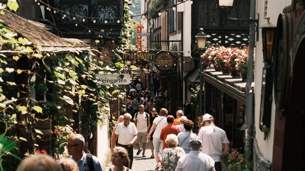 Bustling street scene in Rüdesheim am Rhein, Germany, capturing lively summer tourism and historical architecture.
