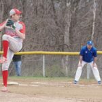 A high school baseball pitcher delivering a pitch during a game outdoors.