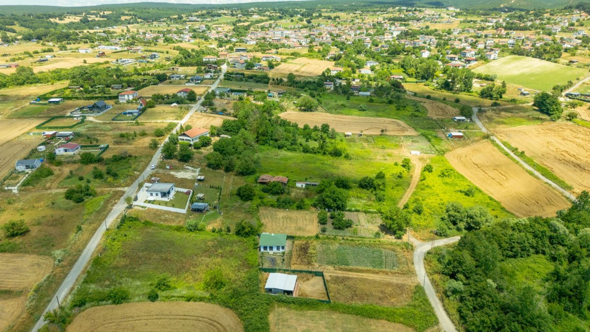 Scenic aerial view of rural countryside with farms, fields, and scattered houses under a clear blue sky.