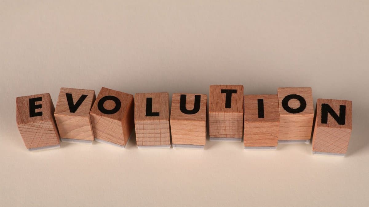 Wooden blocks spelling 'Evolution' on a neutral beige background, symbolizing change and growth.