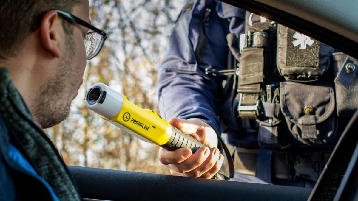 A police officer conducts a breathalyzer test on a driver during a roadside traffic check.