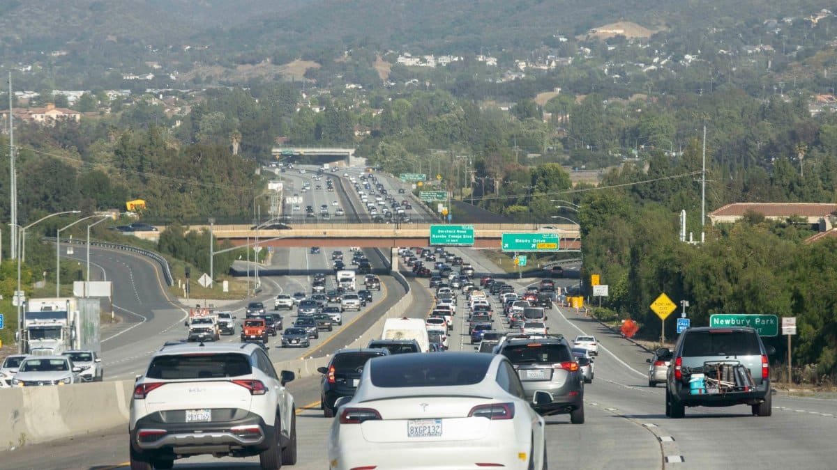 Heavy traffic on a Los Angeles highway with visible road signs and cars under a clear sky.