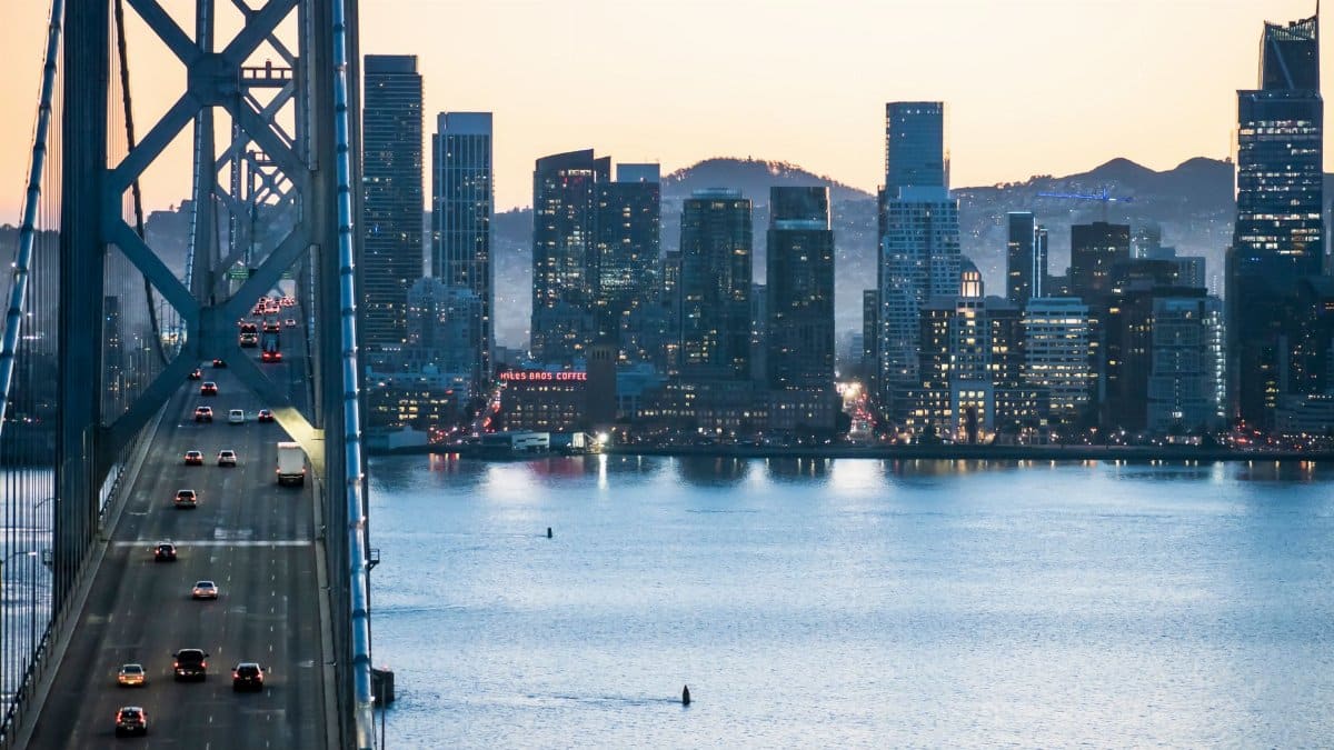 Dusk view of San Francisco skyline with the Bay Bridge and waterfront, showcasing urban architecture.