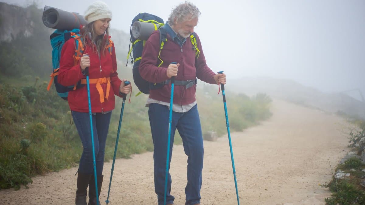 Senior couple backpacking on a foggy trail in Portugal, enjoying an outdoor adventure.