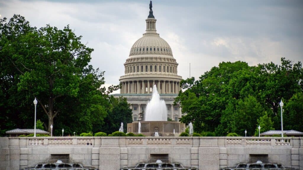 Dramatic view of the US Capitol with a foreground fountain under cloudy skies.