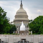 Dramatic view of the US Capitol with a foreground fountain under cloudy skies.