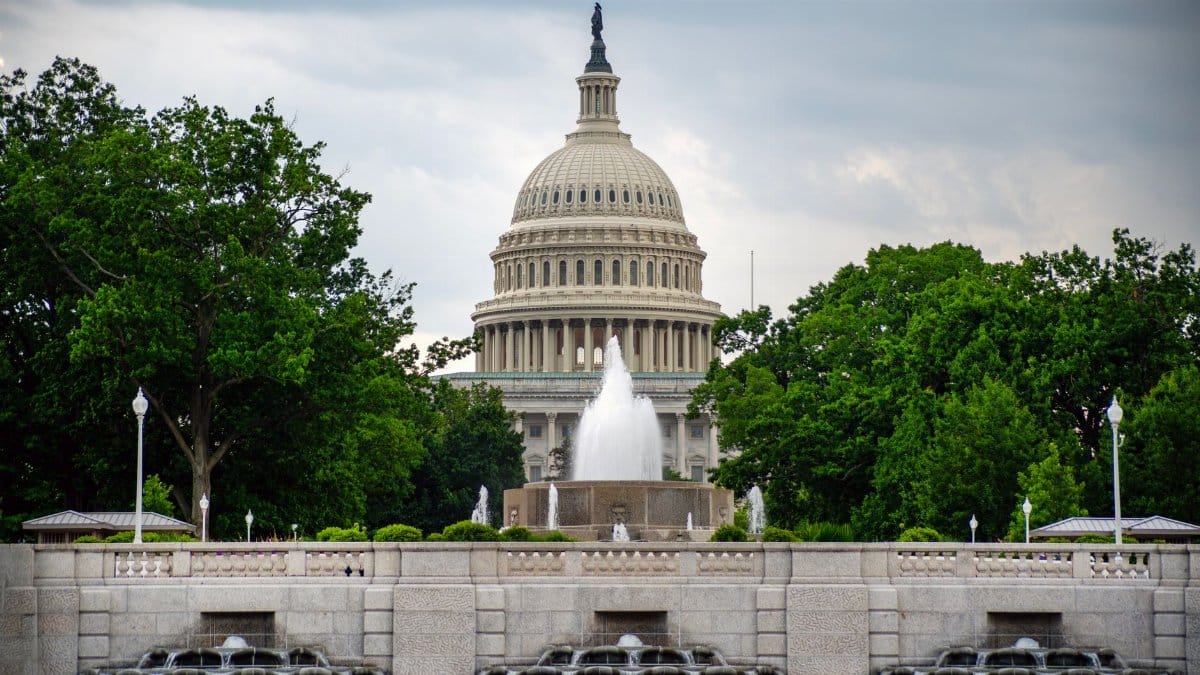 Dramatic view of the US Capitol with a foreground fountain under cloudy skies.