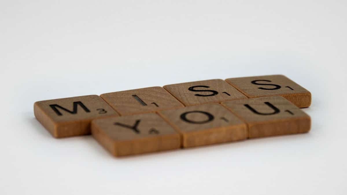 Scrabble tiles arranged to spell 'miss you' on a white background with space for text.