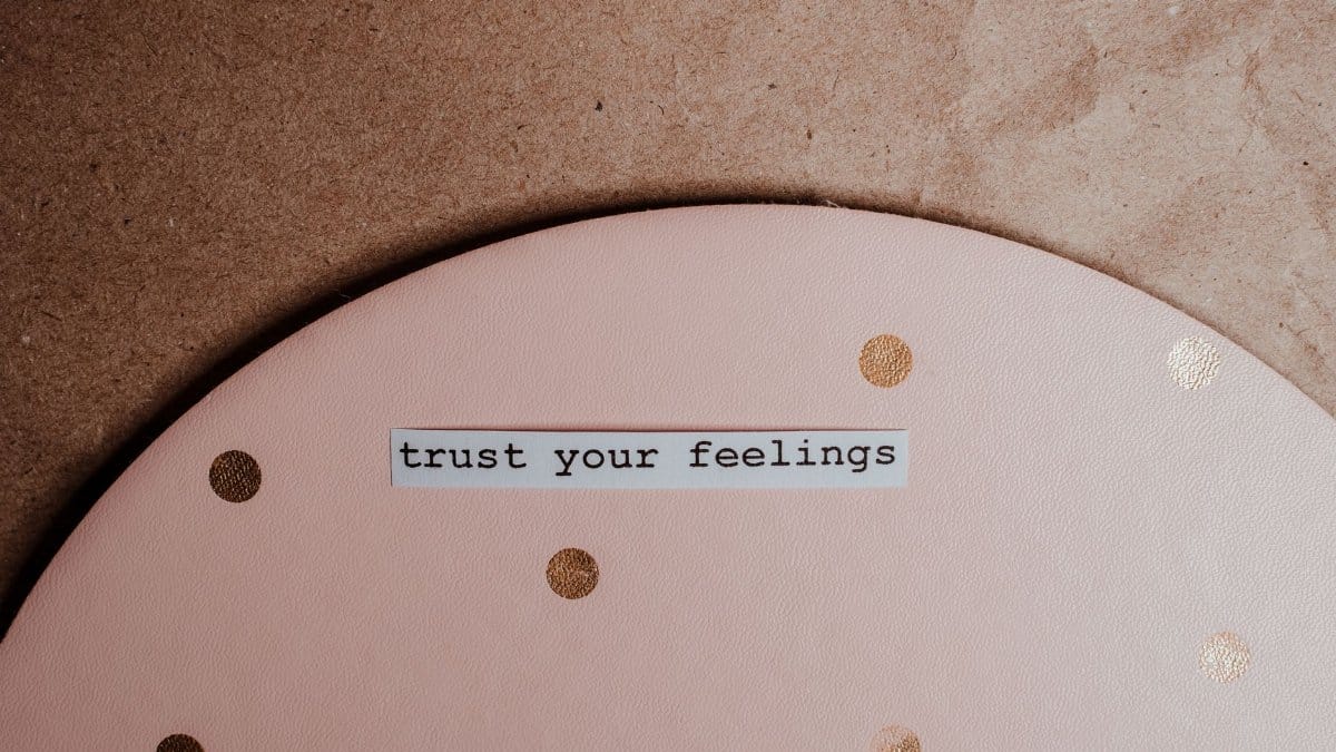 Close-up of a motivational message 'trust your feelings' on a pink polka dot and brown background.