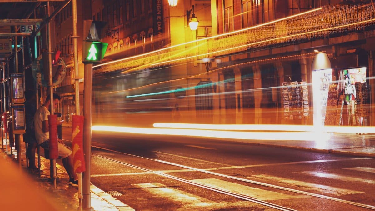 City street at night with motion blur from fast-moving lights, depicting urban life.