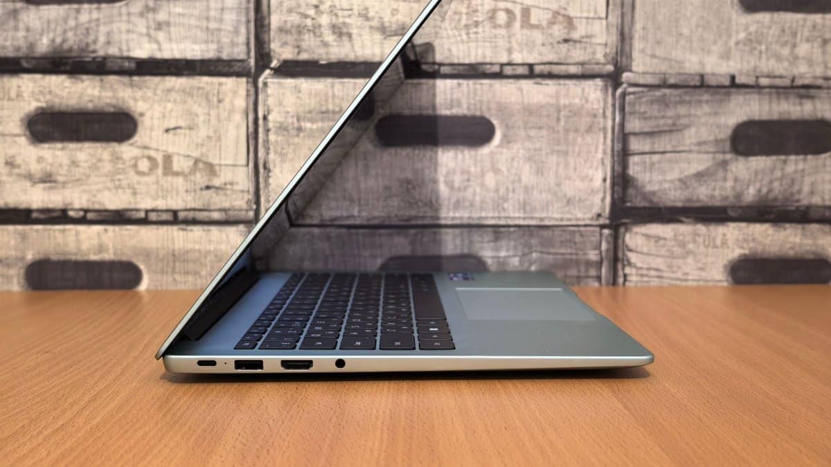 Side view of a sleek modern laptop on a wooden desk with a rustic backdrop.