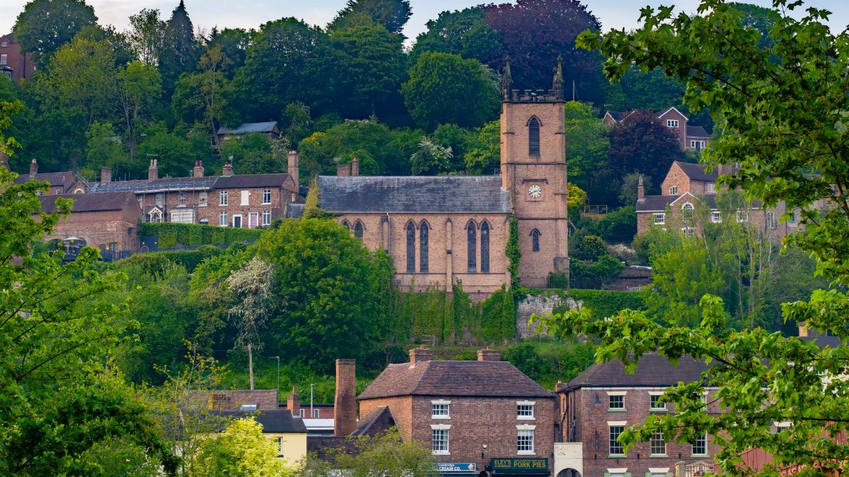 A picturesque view of St. Luke's Church and surrounding greenery in Ironbridge, England.
