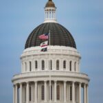 View of California State Capitol dome with American and state flags.