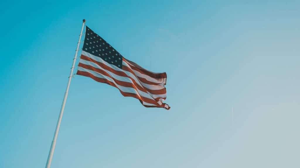 A low angle shot of the American flag waving against a clear blue sky, symbolizing patriotism.