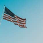 A low angle shot of the American flag waving against a clear blue sky, symbolizing patriotism.