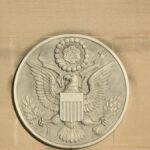 Stone carving of the Great Seal of the United States on a wall displaying an eagle with shield and olive branch.