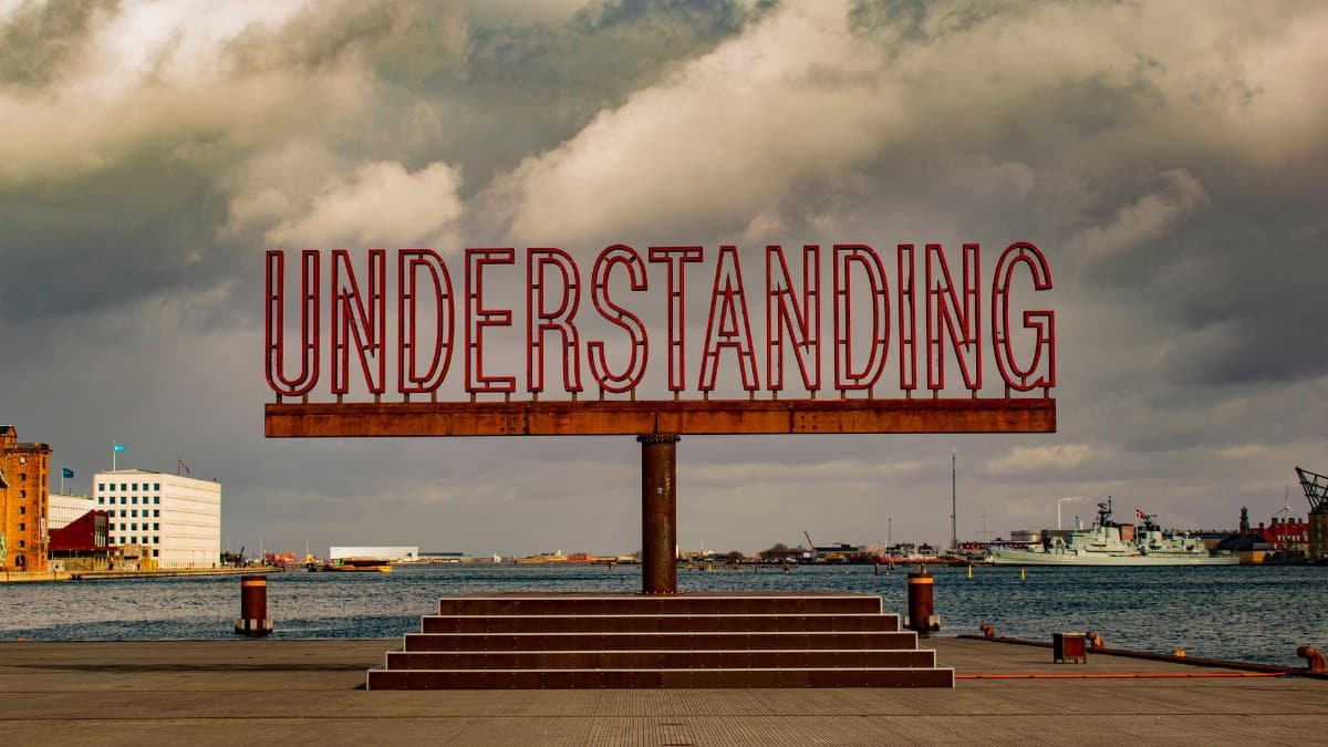 Art installation 'Understanding' at Copenhagen harbor with dramatic clouds.
