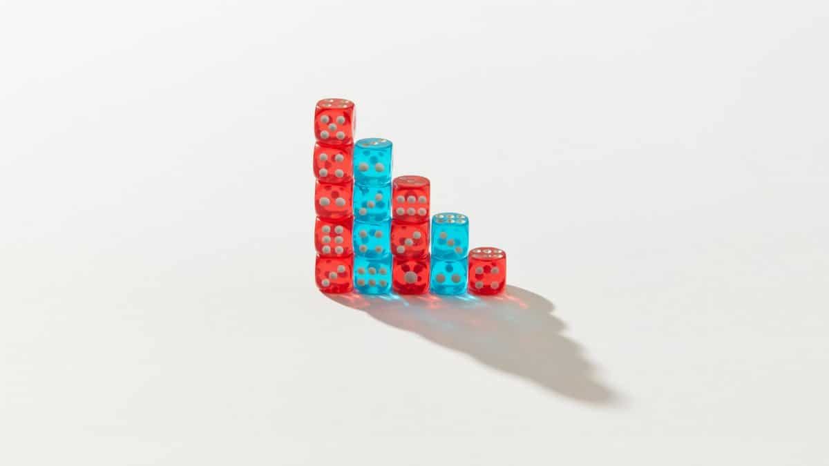 A creative arrangement of red and blue dice stacked in a descending pattern casting a shadow.