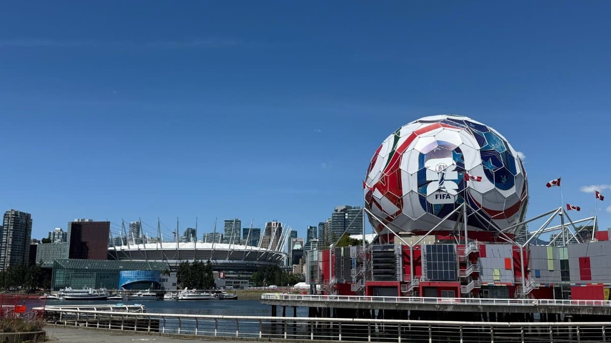 View of Vancouver's Science World featuring FIFA display and BC Place Stadium under a clear blue sky.