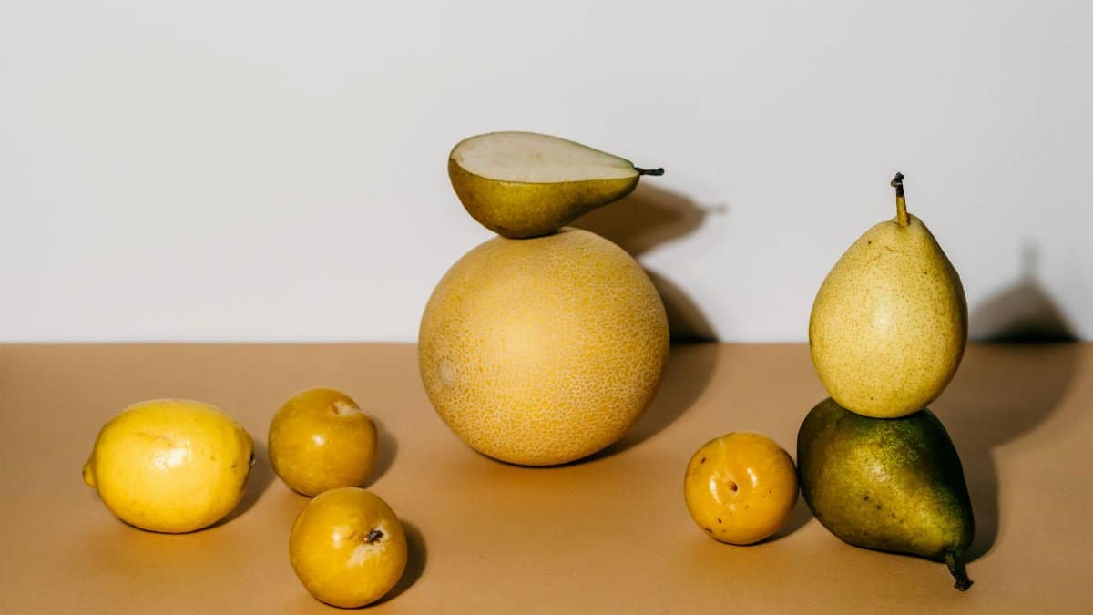 A composition of pears and citrus fruits in a minimalist still life photography setting.