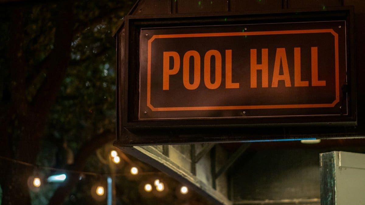 A glowing pool hall sign illuminated by string lights at night, creating a cozy atmosphere.