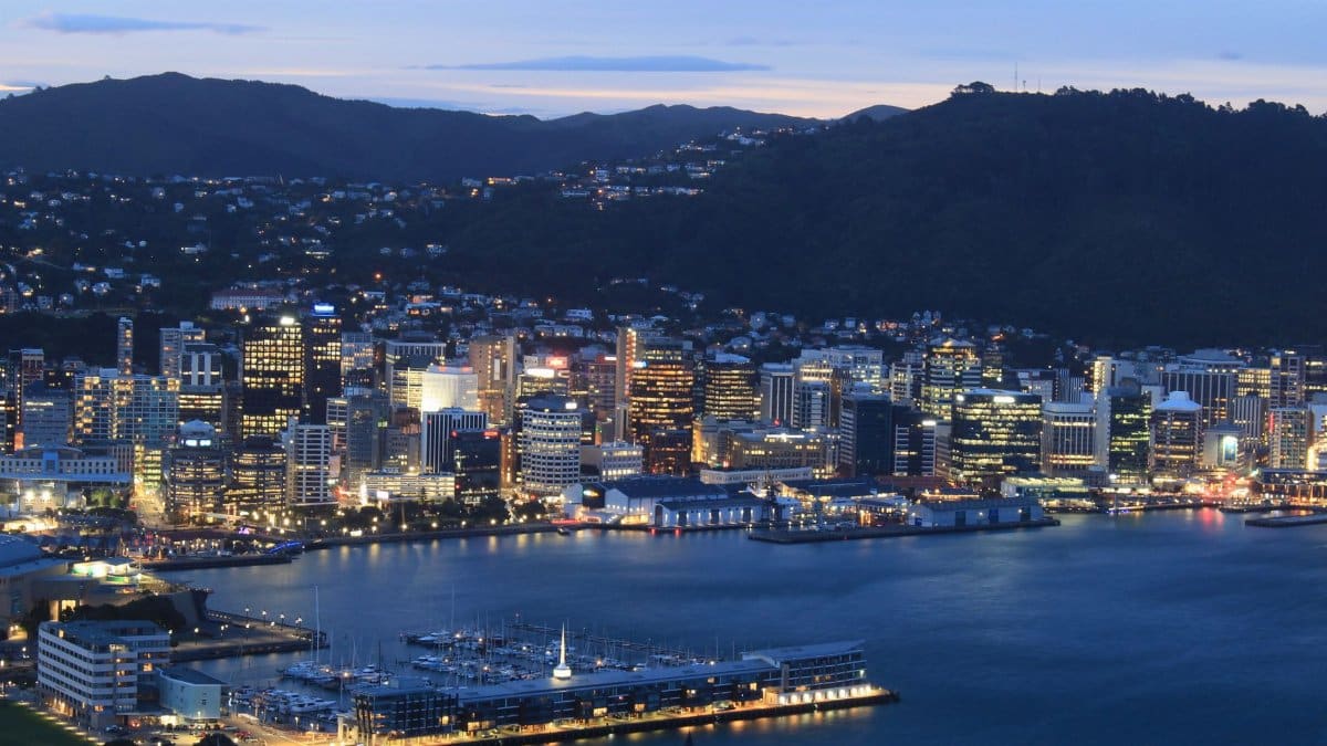 A striking evening aerial view of Wellington city skyline with vibrant lights reflecting on the waterfront.