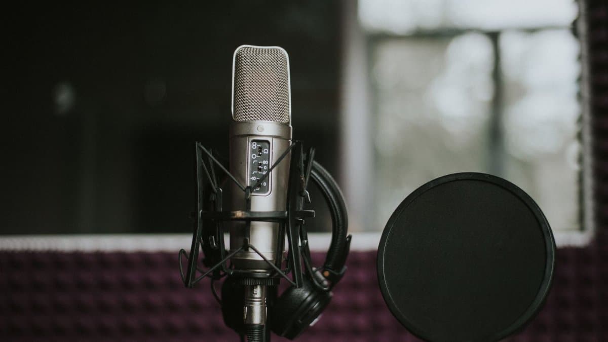 Close-up of a microphone with pop filter in a modern music studio environment.