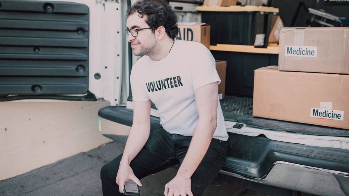 A volunteer sitting in a van organizing medicine boxes for shipment.