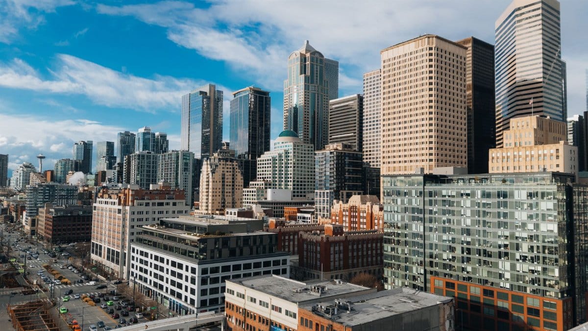 Aerial view of downtown Seattle's skyline featuring iconic skyscrapers under a bright blue sky.
