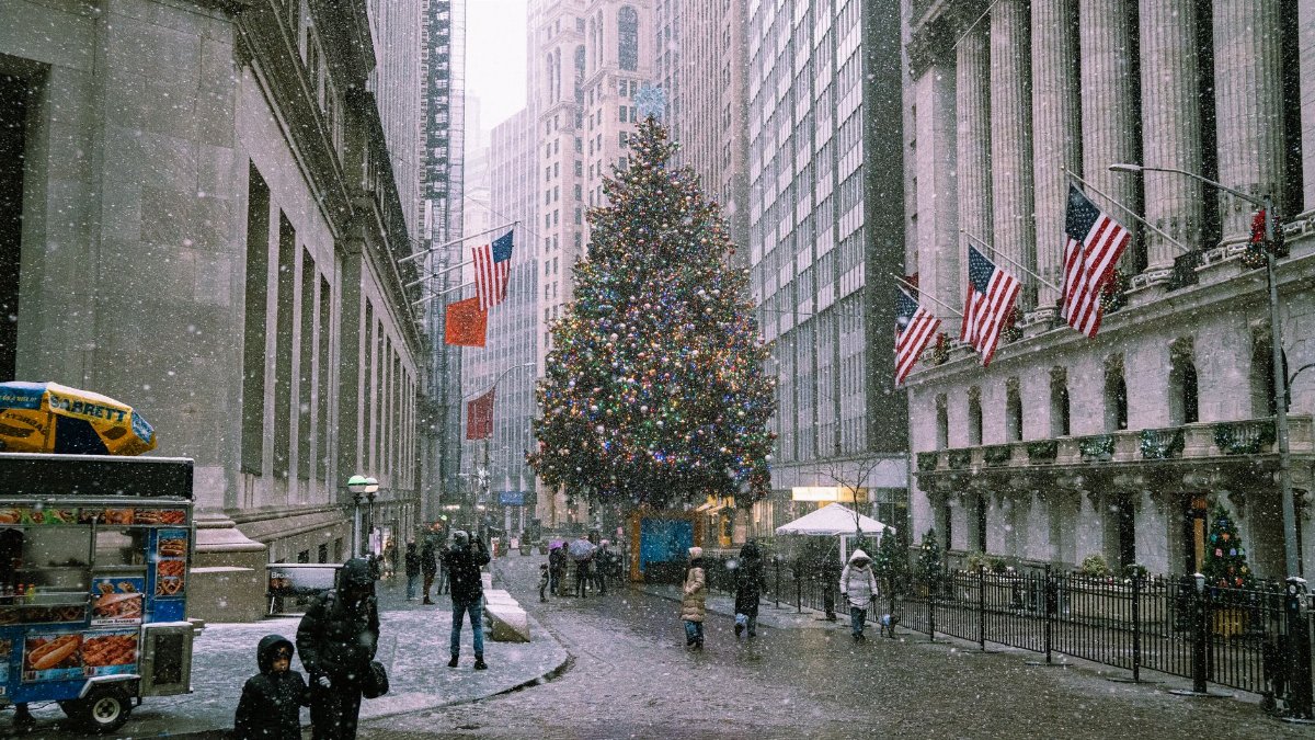 A snowy winter scene in New York City with a decorated Christmas tree and bustling street life.