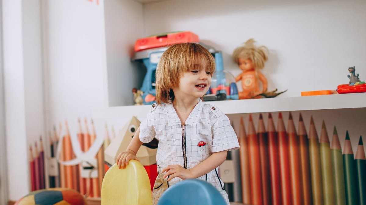 Smiling child enjoys playtime in a vibrant, creative preschool classroom environment.