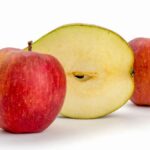 Red apples and a sliced apple against a clean white backdrop.