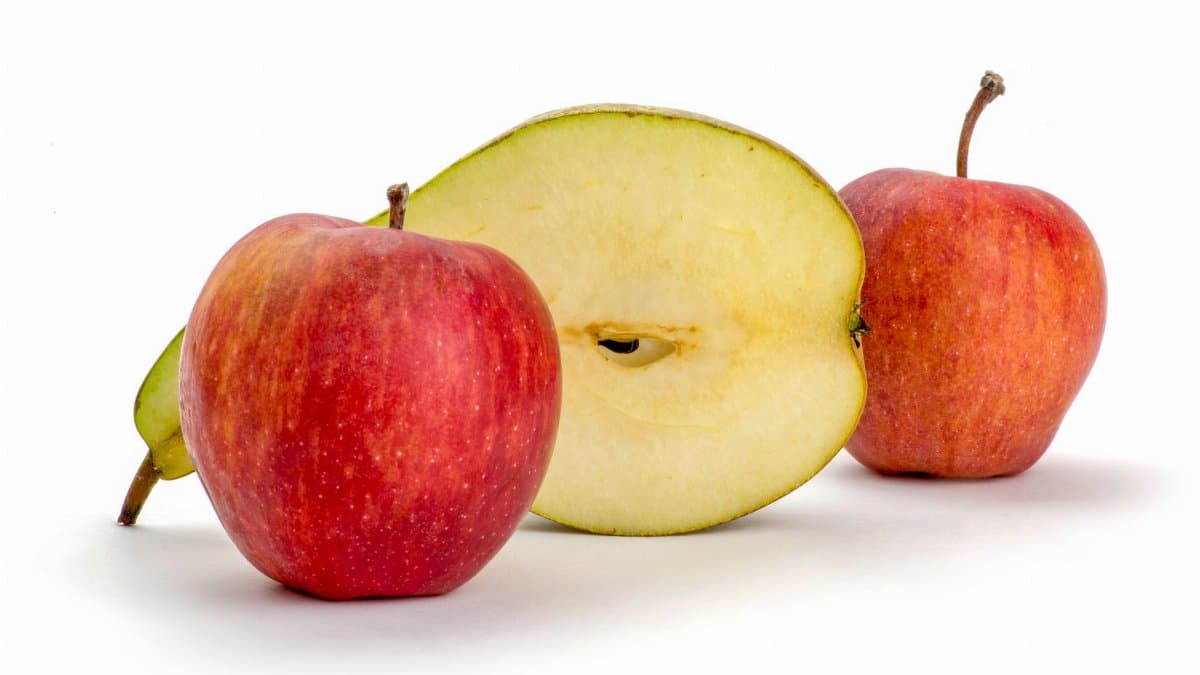 Red apples and a sliced apple against a clean white backdrop.