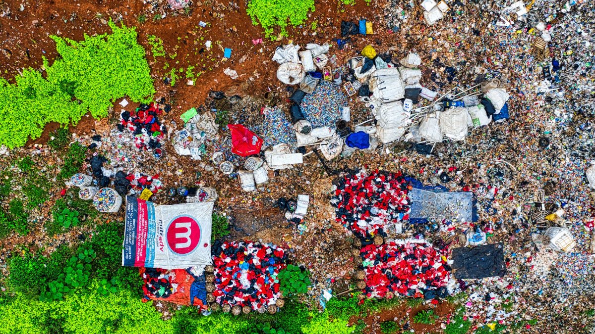 An aerial shot showing piles of waste in a dumpsite surrounded by greenery in Banten, Indonesia.