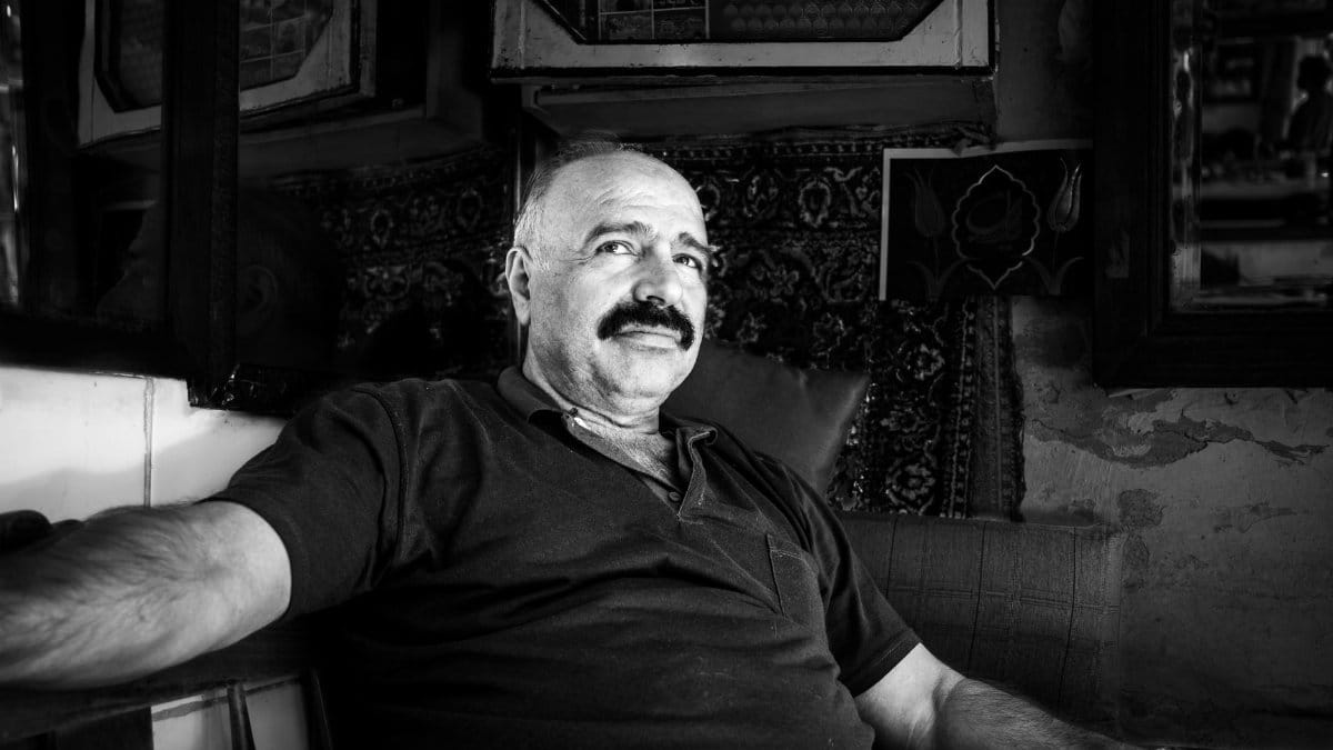 Black and white portrait of a middle-aged man with a mustache sitting in a traditional interior.