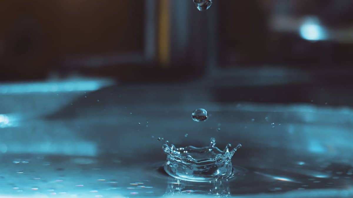 Close-up capture of water droplets splashing with a vibrant blue tone.