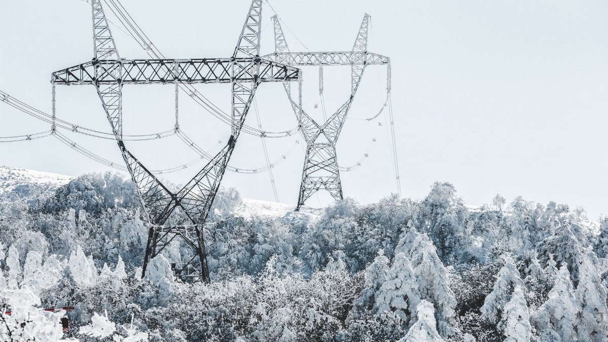 A scenic view of transmission towers amidst snow-covered trees during winter.