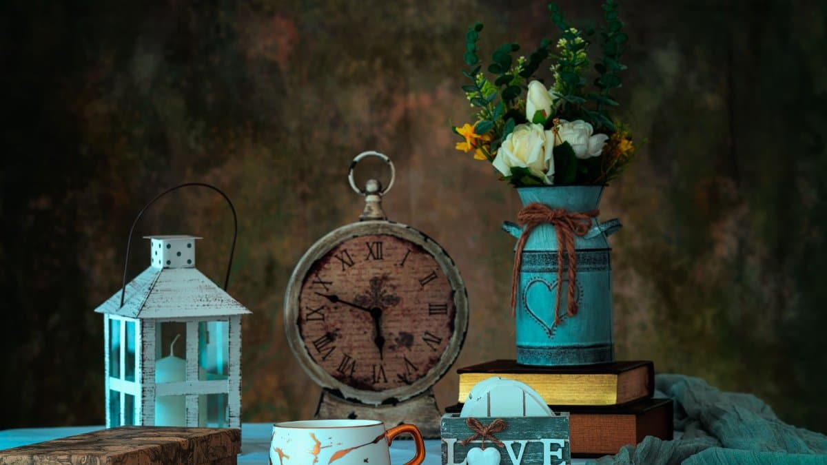 A charming still life arrangement featuring a vintage clock, lantern, and floral vase.