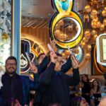Guests celebrate in a vibrant, upscale venue with 'Welcome To The Eye' signs and festive atmosphere.
