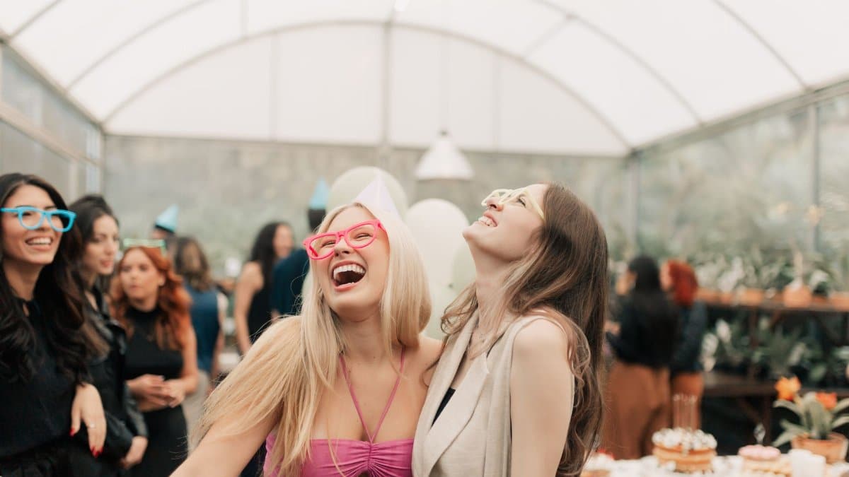 Lively indoor party scene capturing joyful friends sharing laughter and wearing colorful glasses.