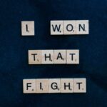 Wooden Scrabble tiles on dark background spelling 'I won that fight.'