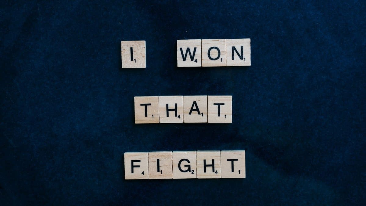Wooden Scrabble tiles on dark background spelling 'I won that fight.'