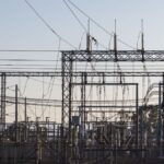 High-voltage electrical substation with steel structures and power lines at dawn.